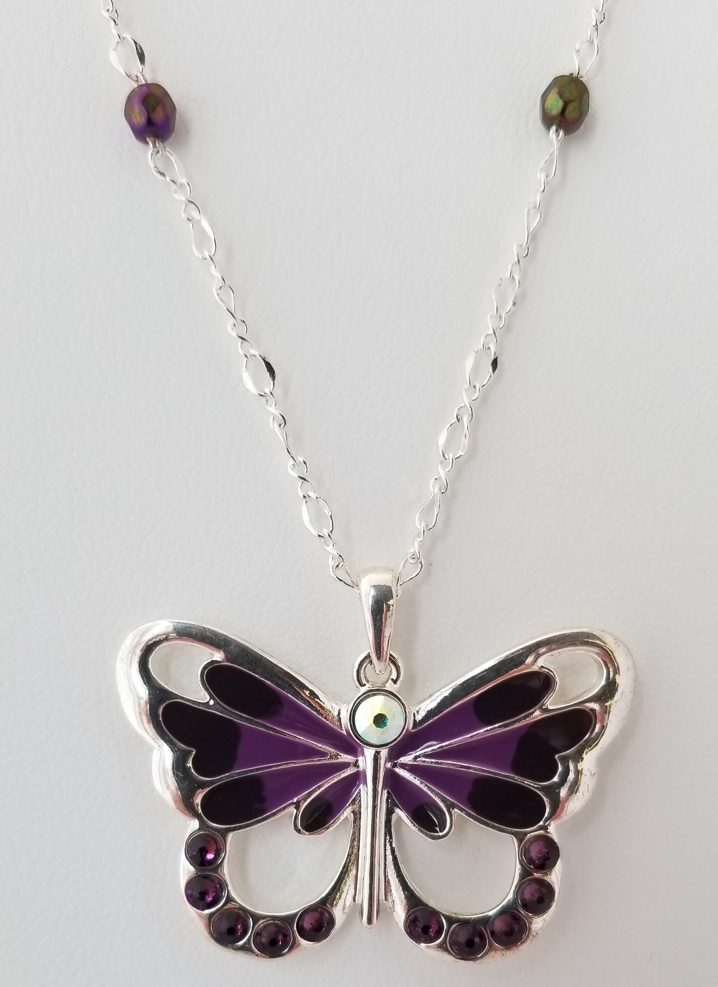 A silver butterfly pendant necklace with purple gemstones.