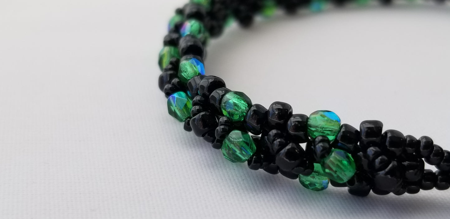 a green and black beaded necklace on a white surface