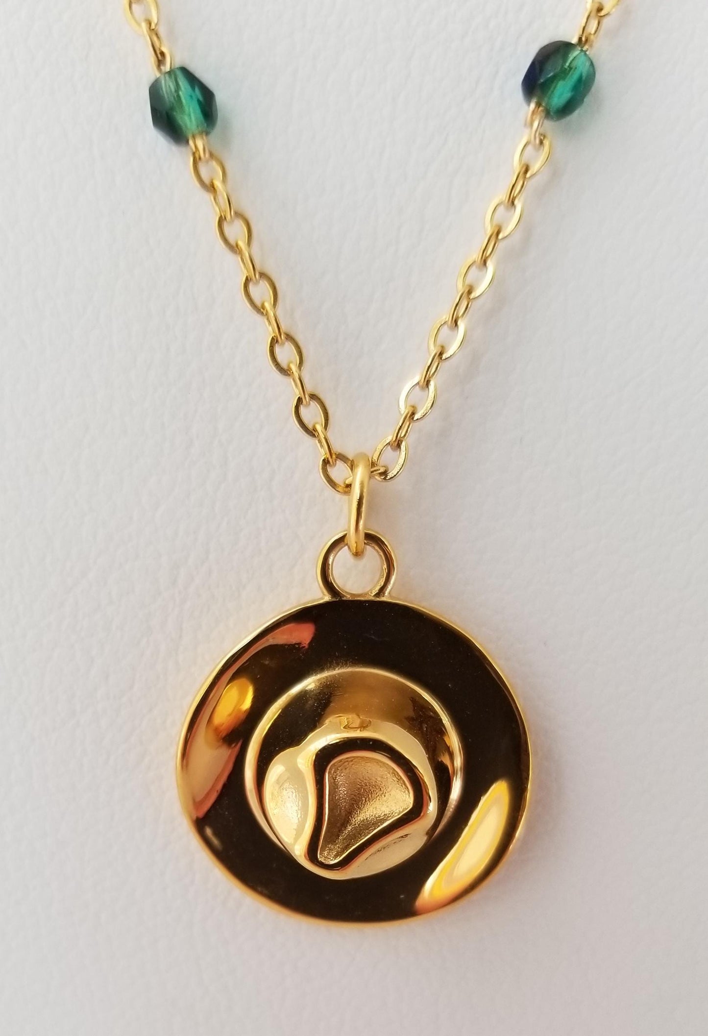 A gold-colored pendant necklace with a circular design featuring a heart-shaped element in the center.
