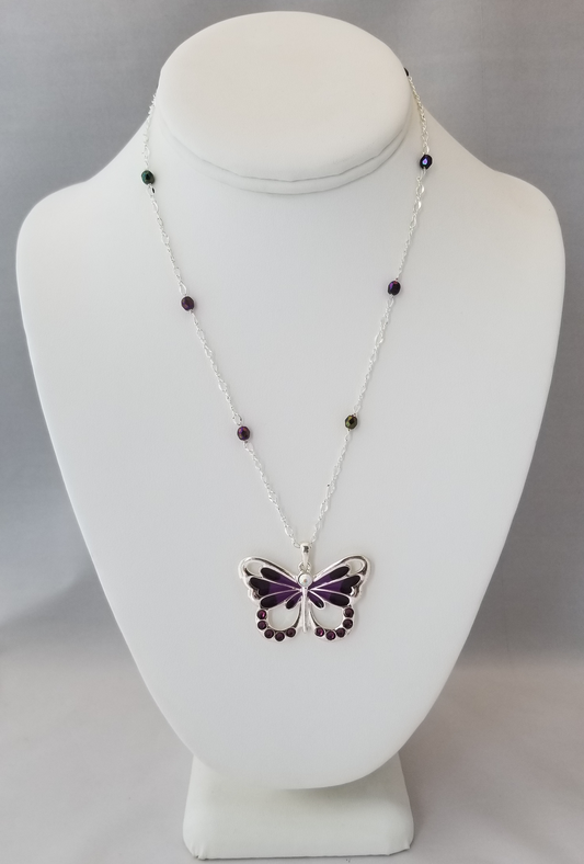 A white bust form on which a necklace with a butterfly pendant is displayed.