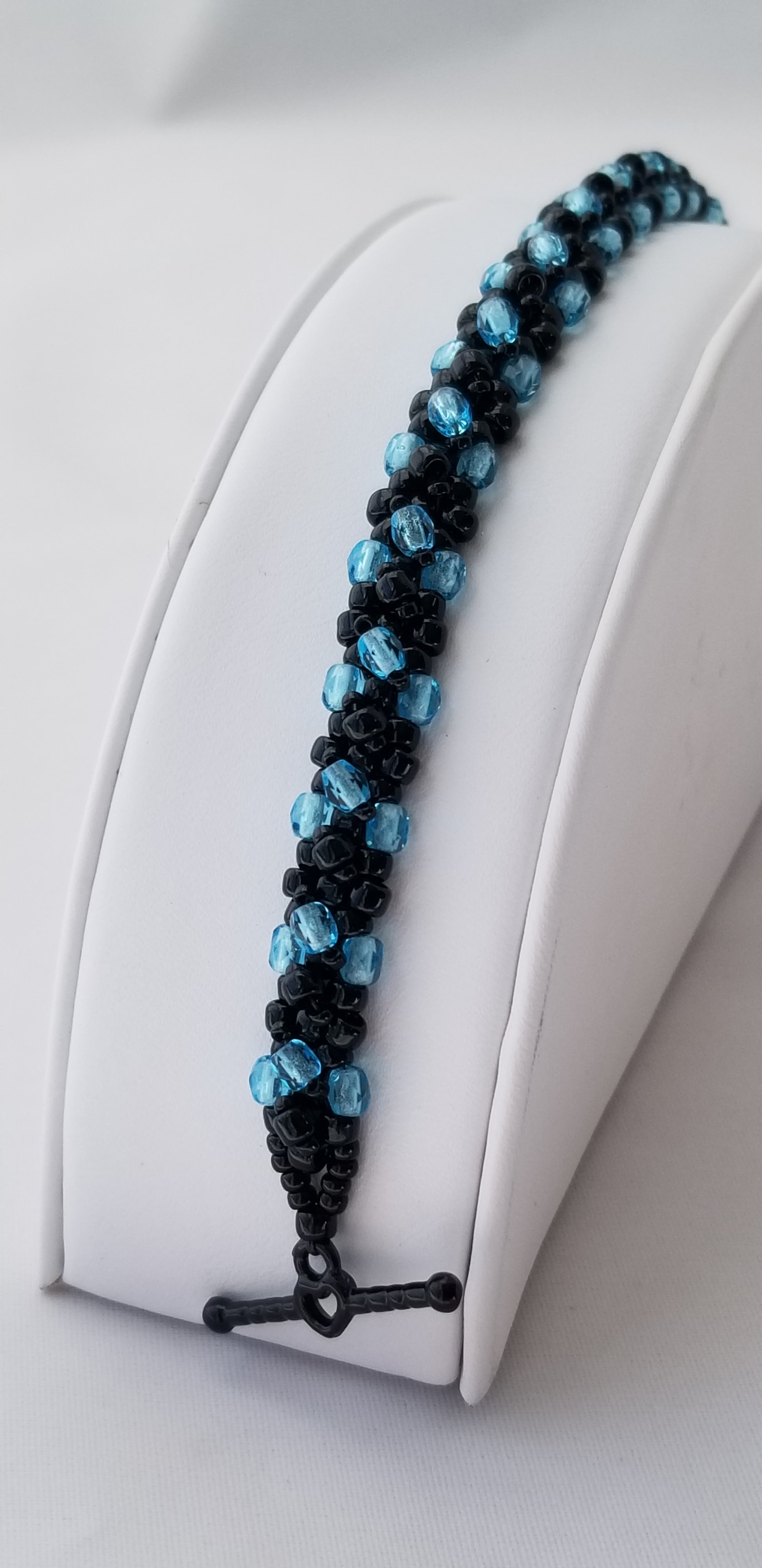 a blue and black beaded necklace on a white mannequin