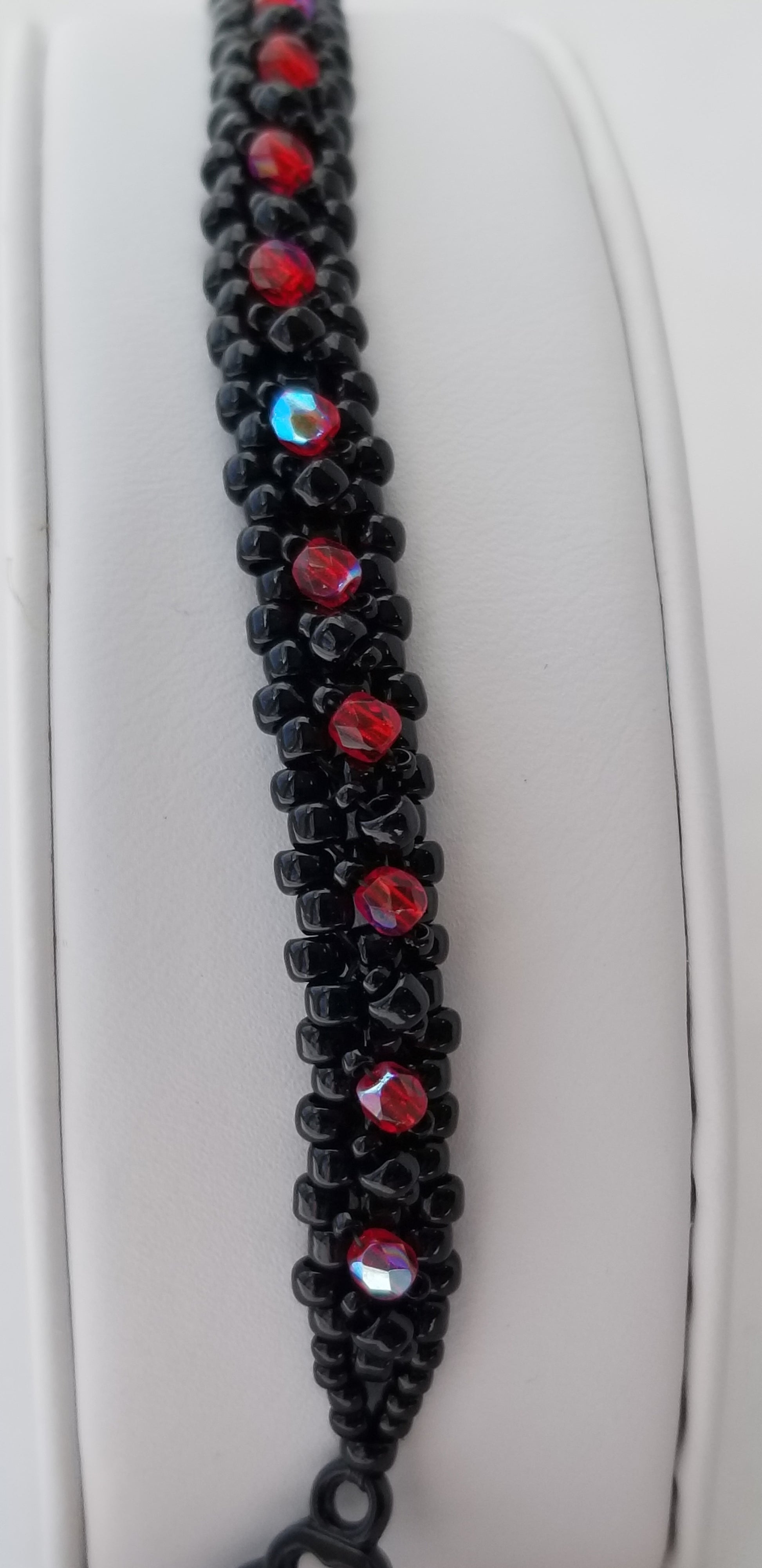 a black and red beaded bracelet on a white surface