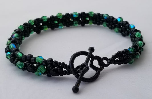 a black and green beaded bracelet with an anchor