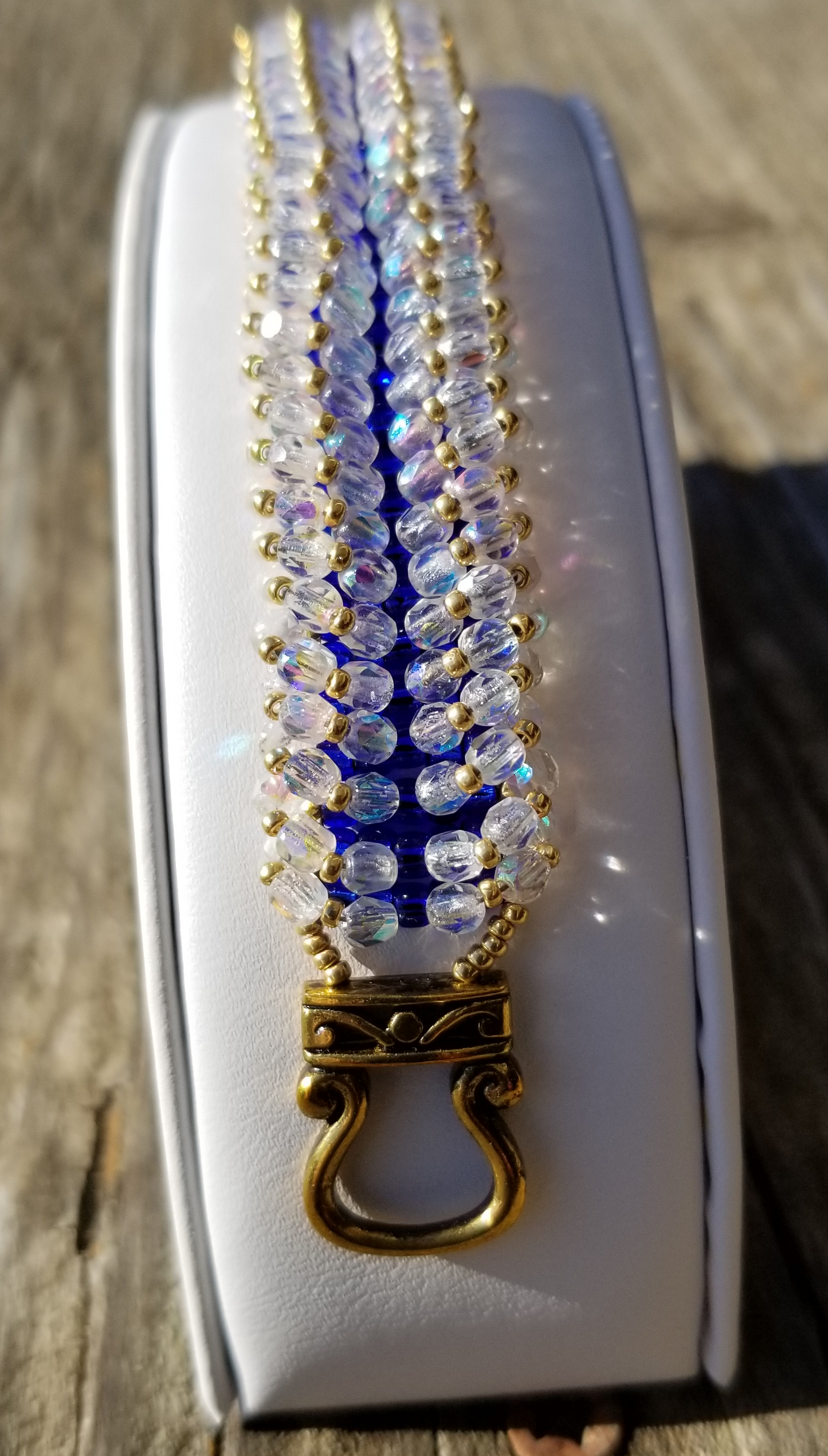 a white case with a blue and gold necklace on it